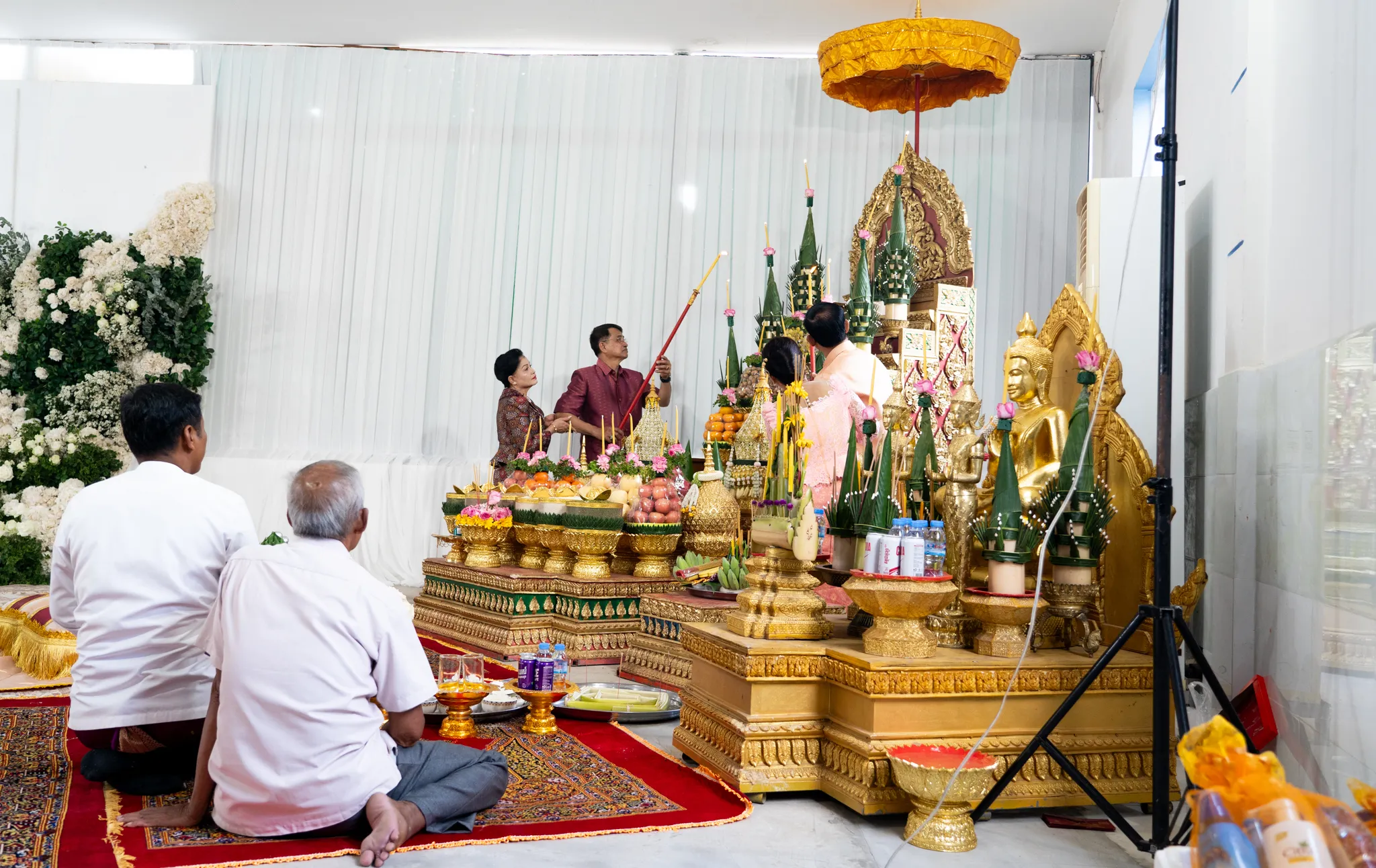Family kneels in prayer before a gilded Buddhist shrine