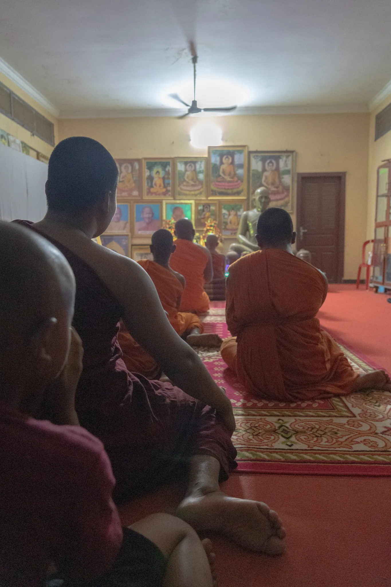 Evening prayers beneath rows of Buddha images