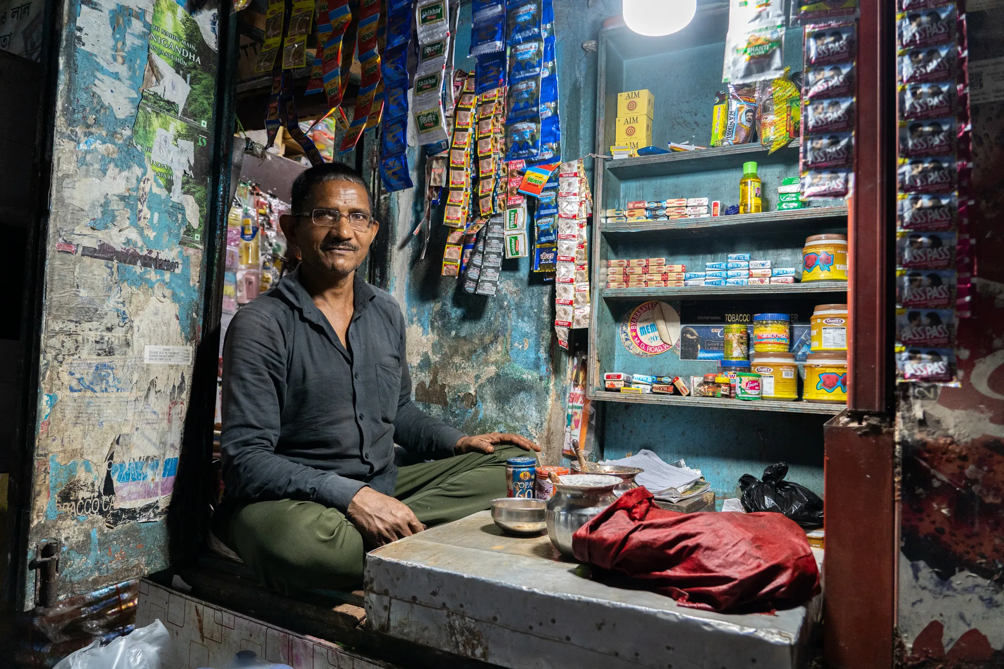 Shopkeeper, shelves stacked to the ceiling, India