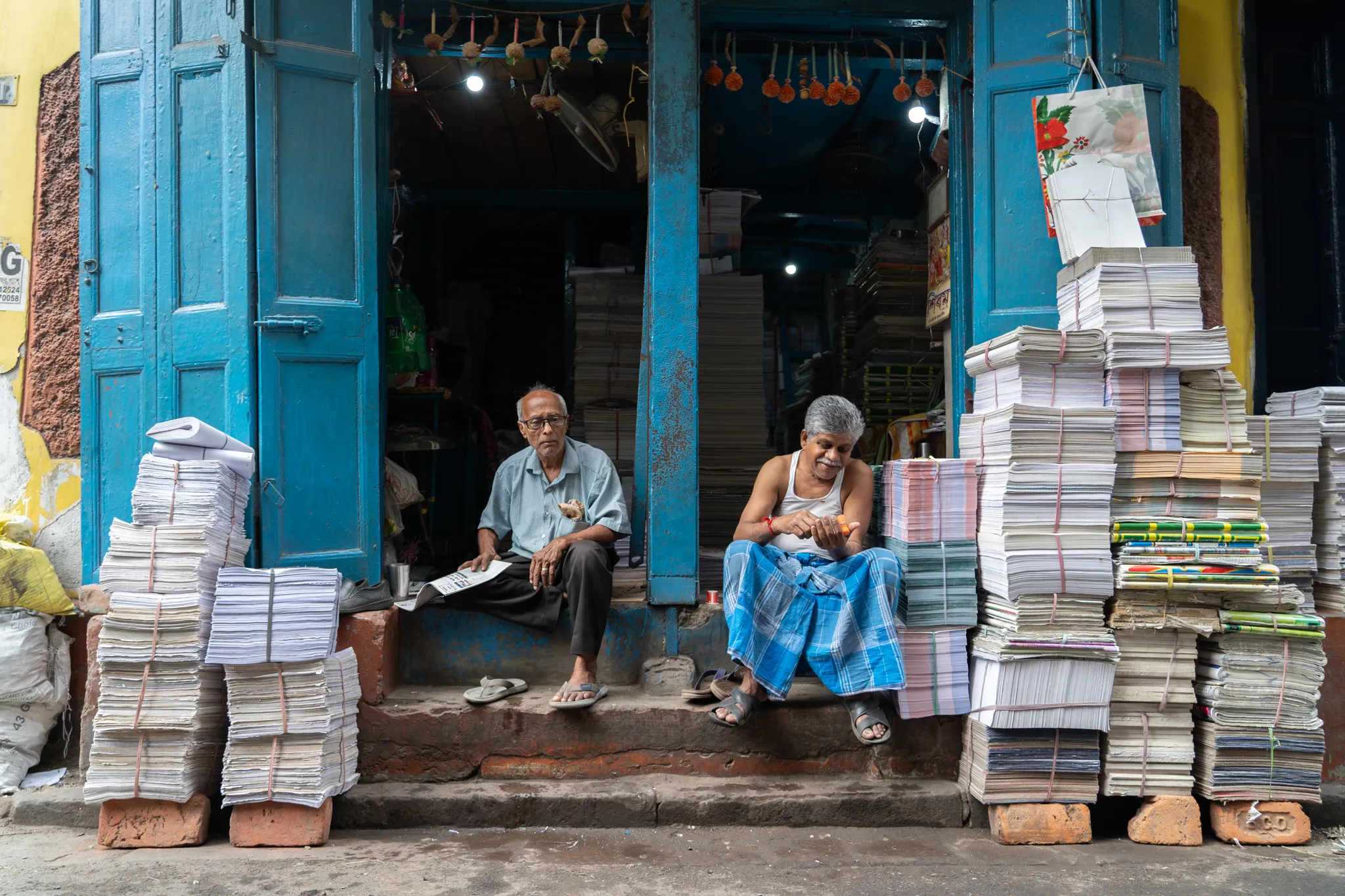 Paper sellers pause on the shop steps