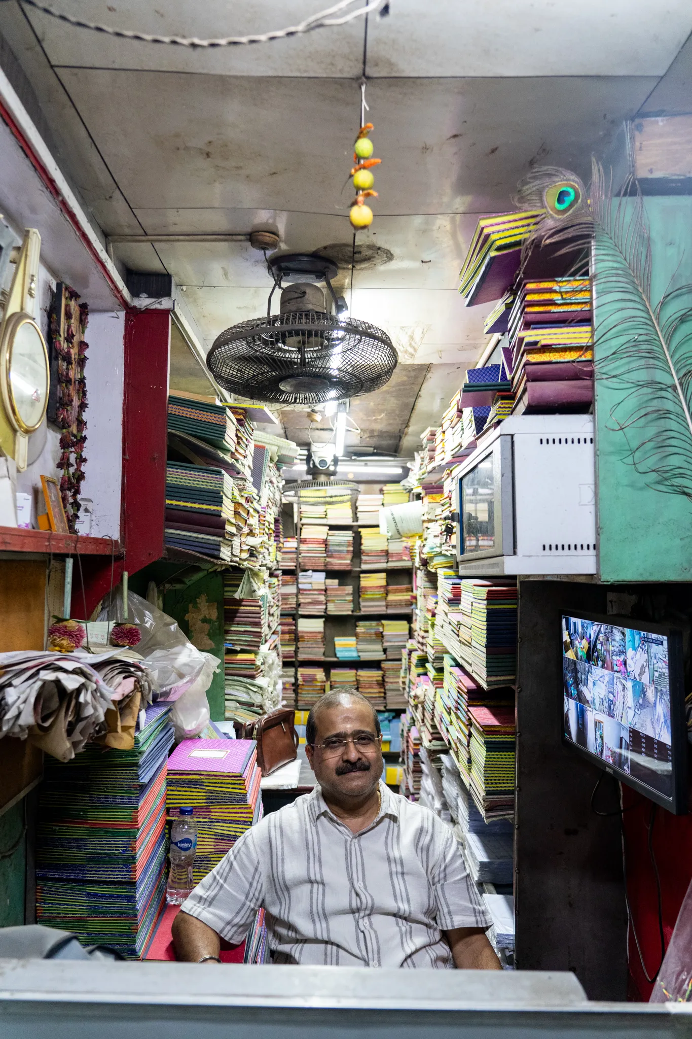 shopkeeper beneath a ceiling fan, India