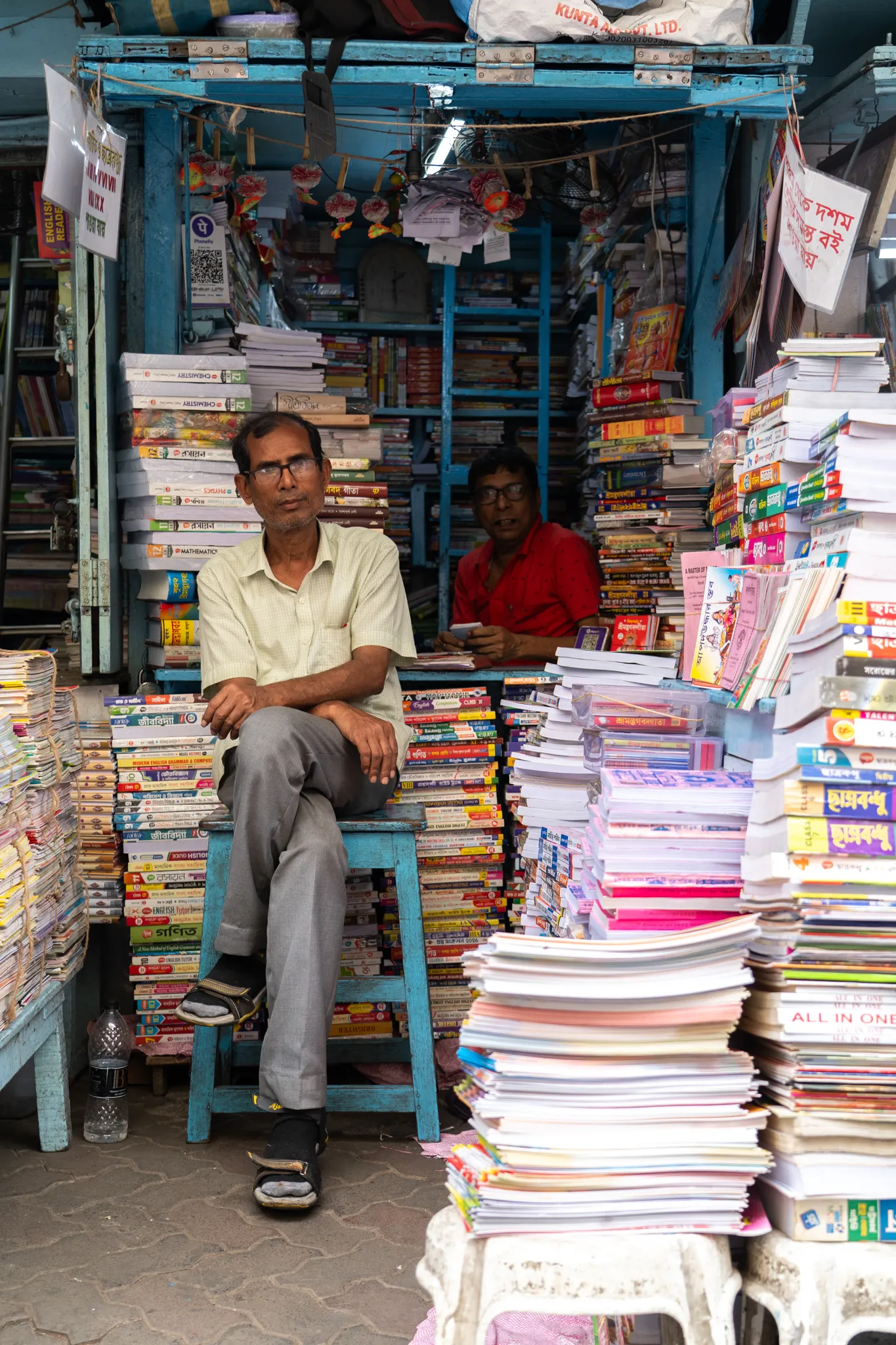 Bookseller among stacks of paperbacks, India