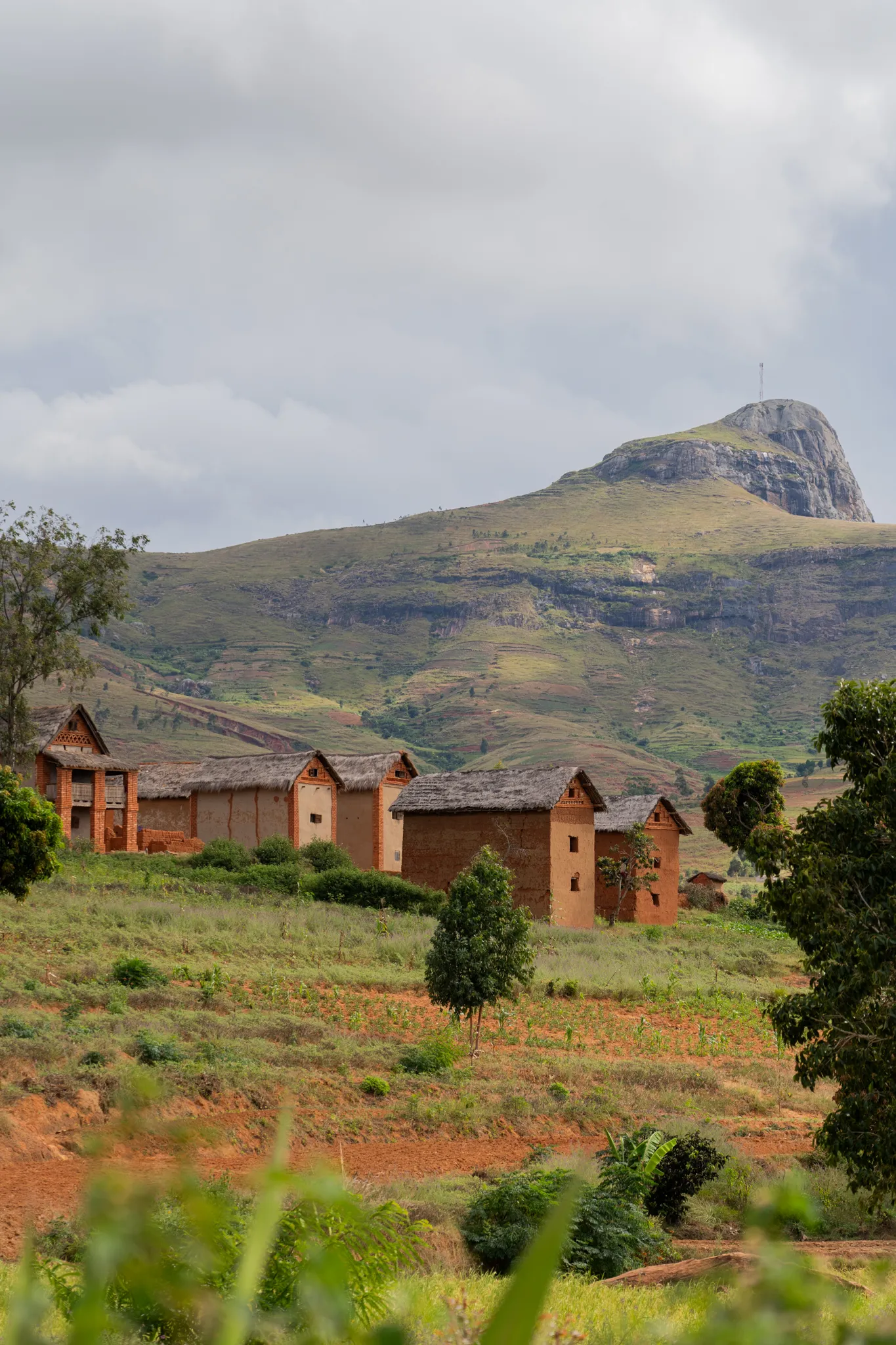 Row of traditional homes below a rocky peak, Madagascar