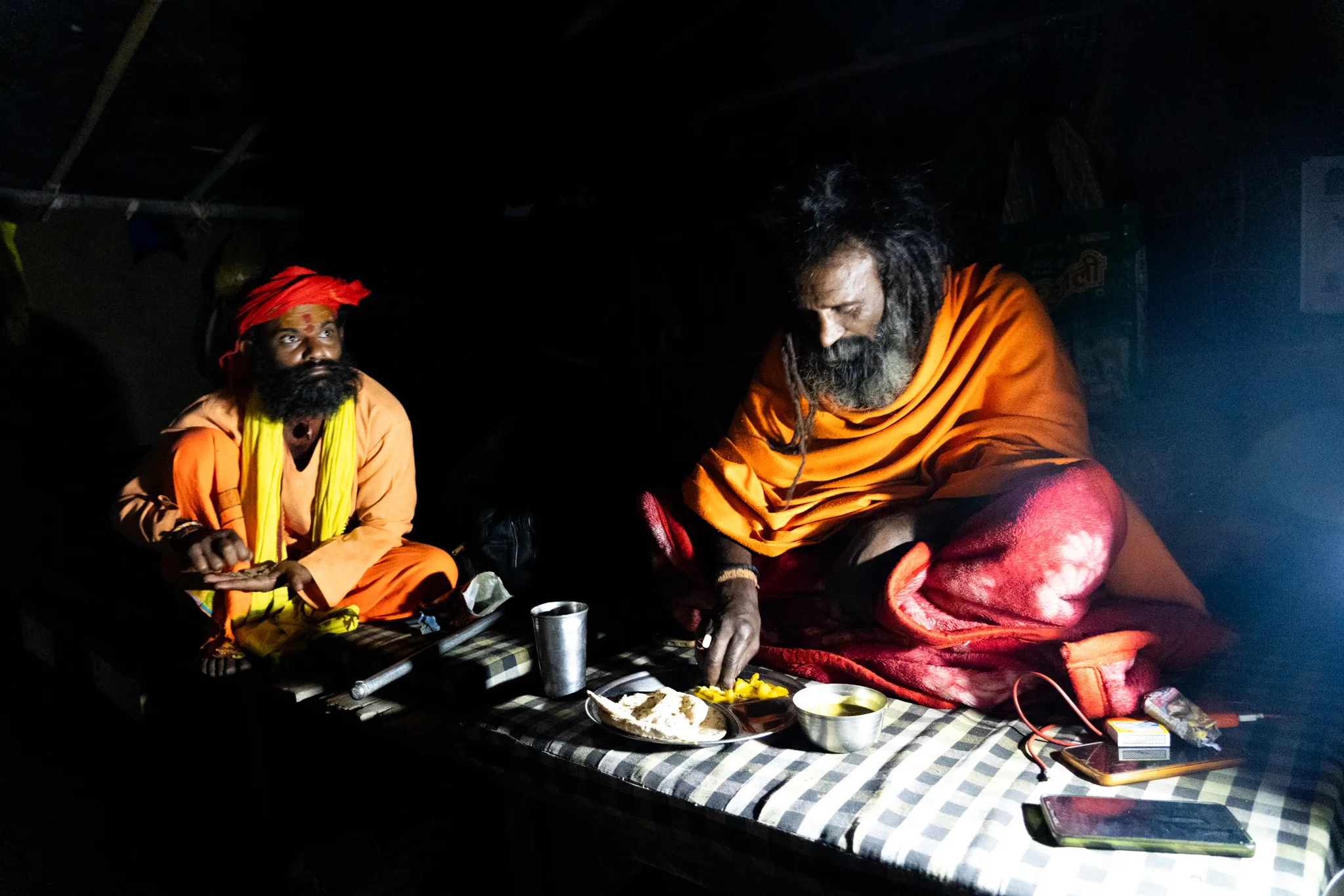 Sadhus sharing a meal by lamplight