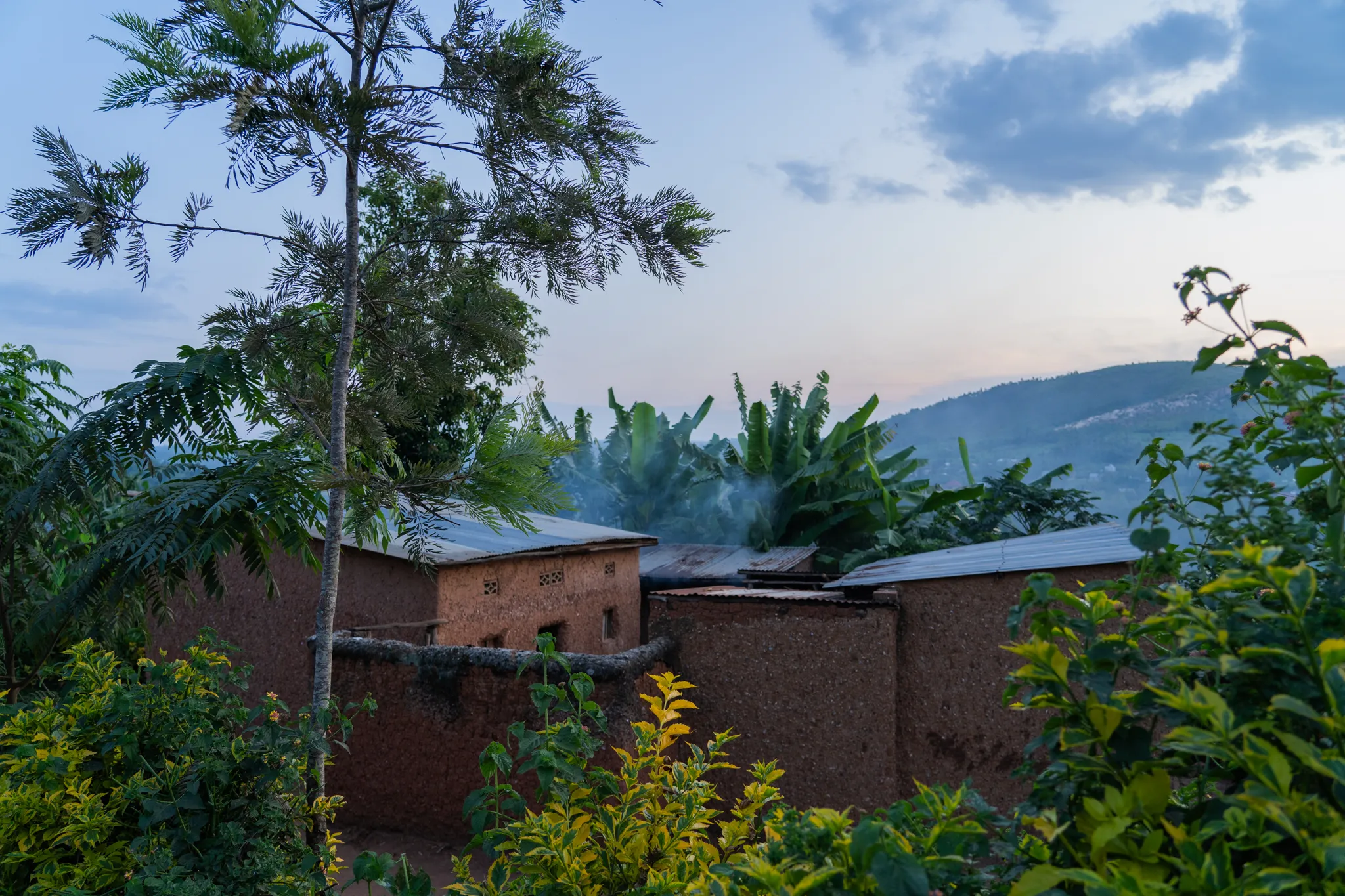 Mud-brick homestead at dusk, smoke rising, Rwanda