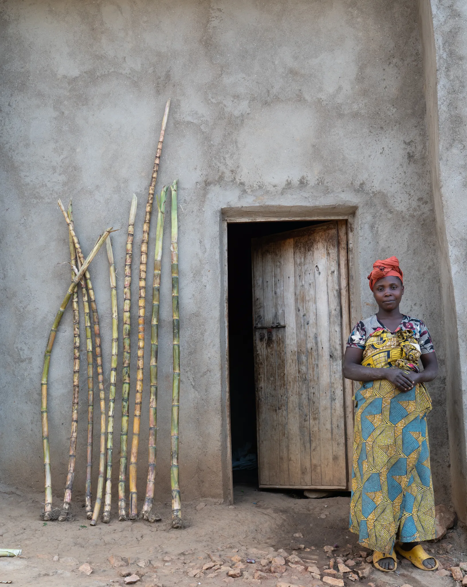 Woman beside sugarcane stalks against the wall, Rwanda