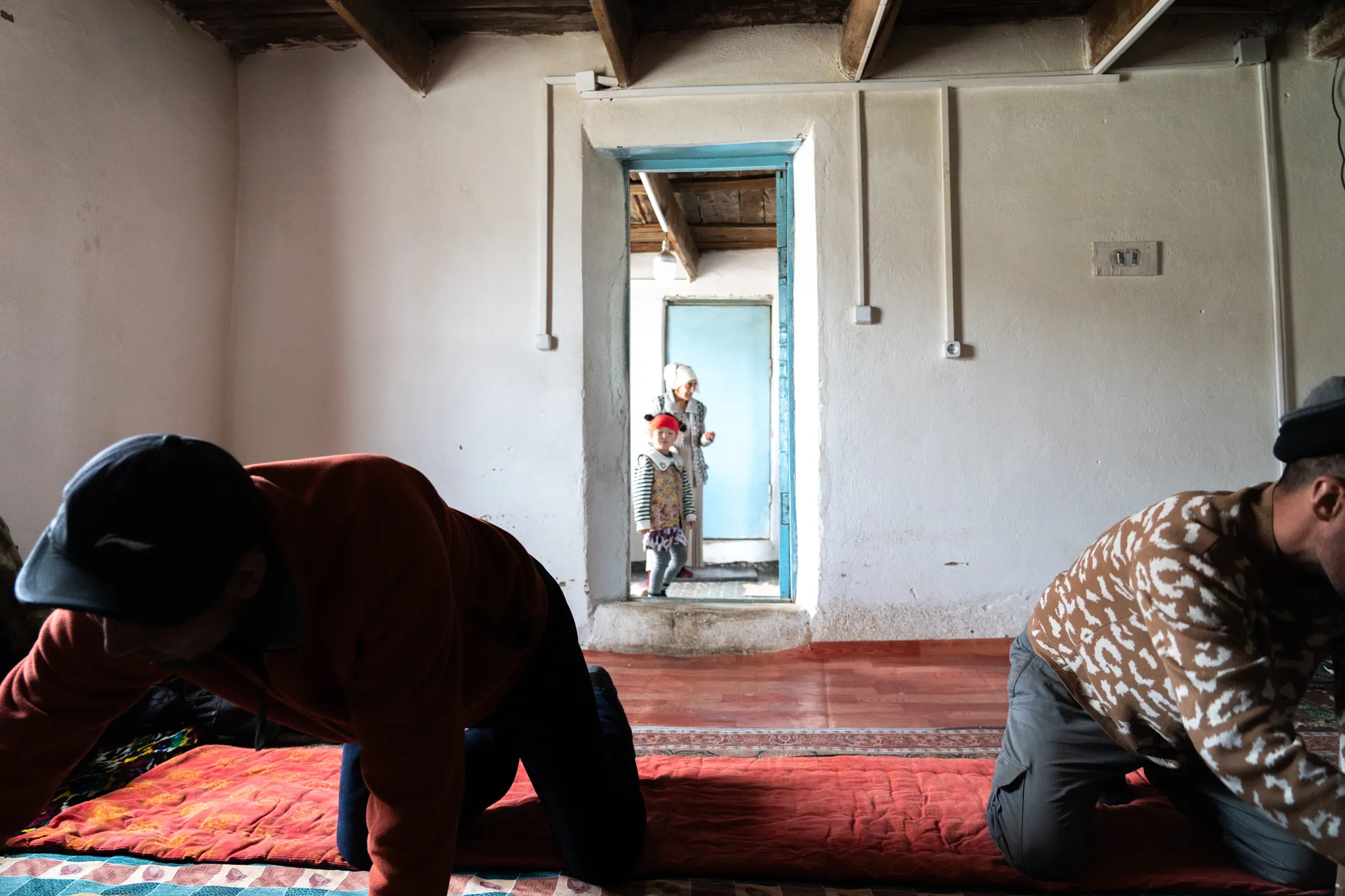 Men sort through bread and sweets while women enter from the back during Eid al-Adha, Tajikistan