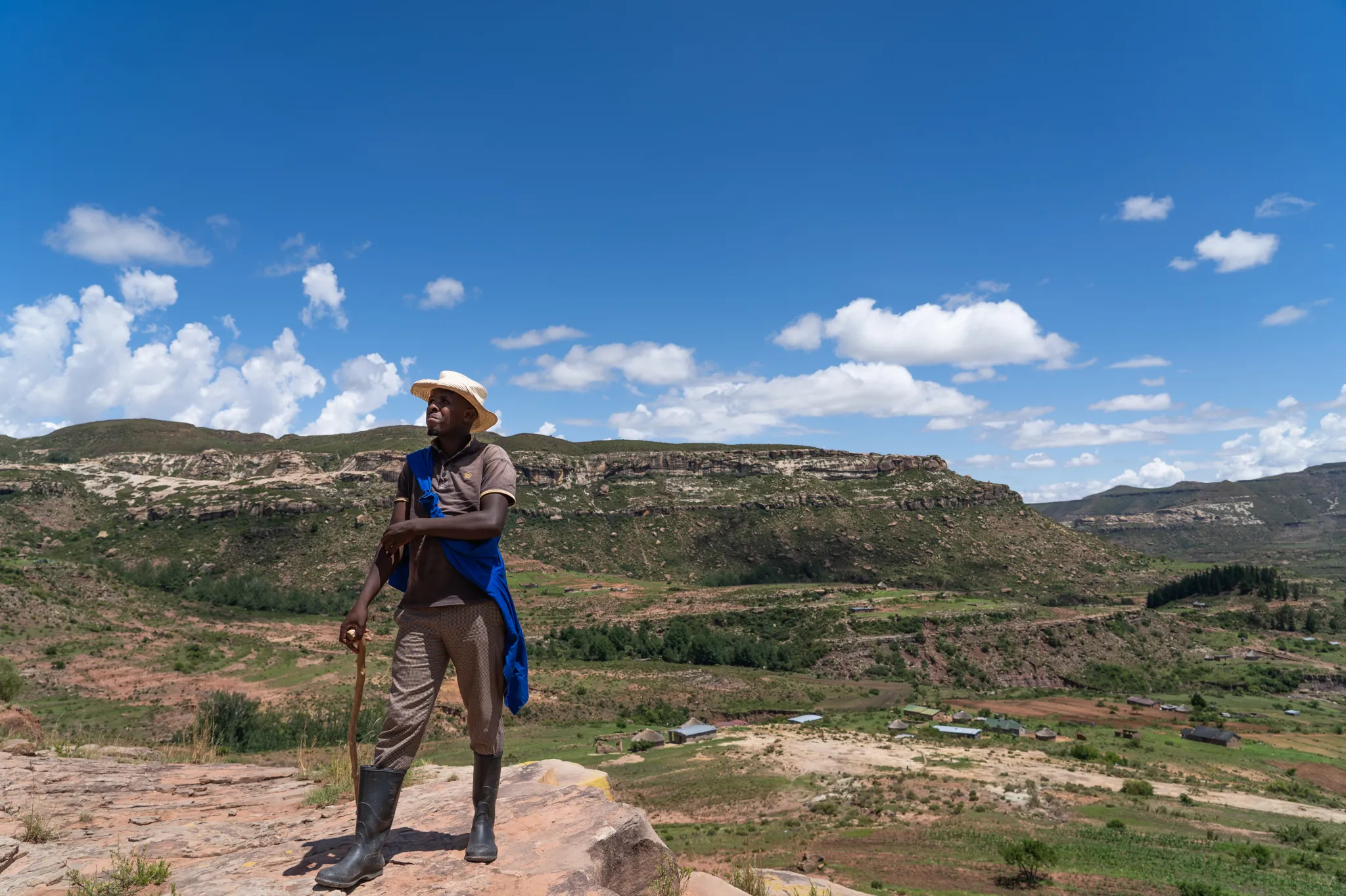 Herder pauses on a cliff above a wide valley