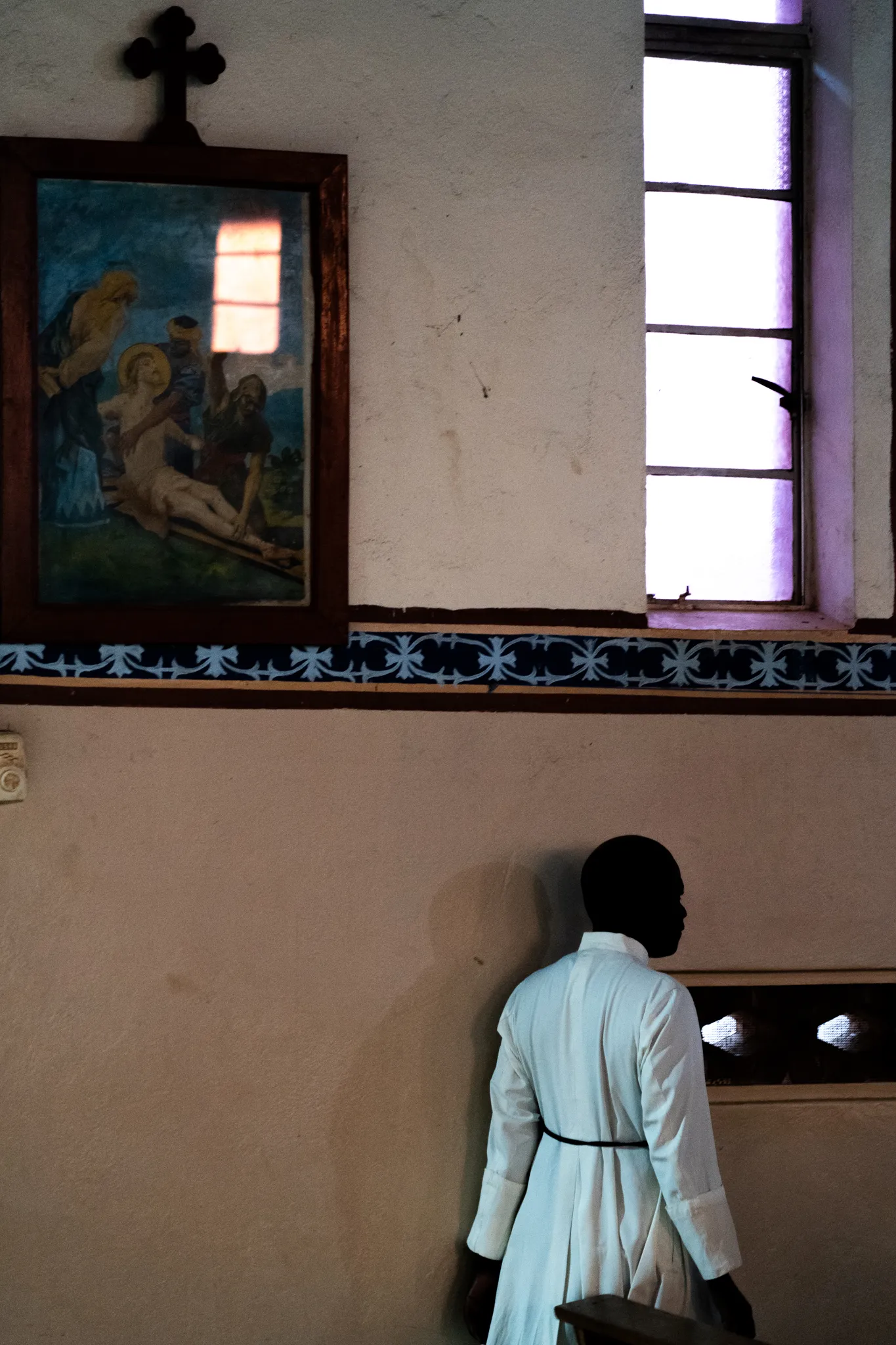 Christian monks passing religious paintings in a village church, Uganda