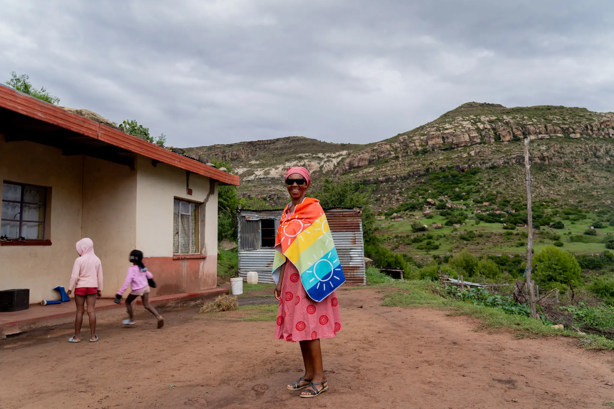 Woman in a bright blanket outside her home, Lesotho