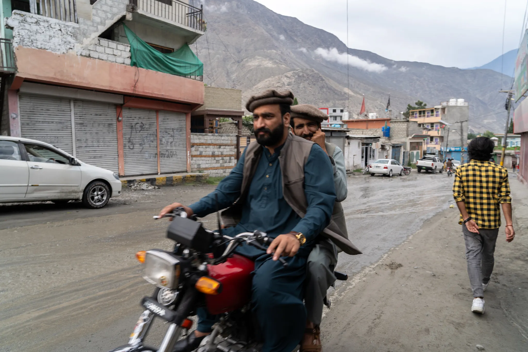 Two men riding a motorcycle through town, Pakistan
