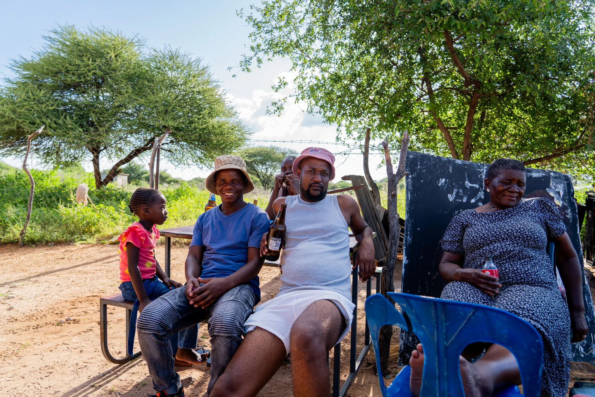 Family gathers under a tree, sharing drinks and laughter