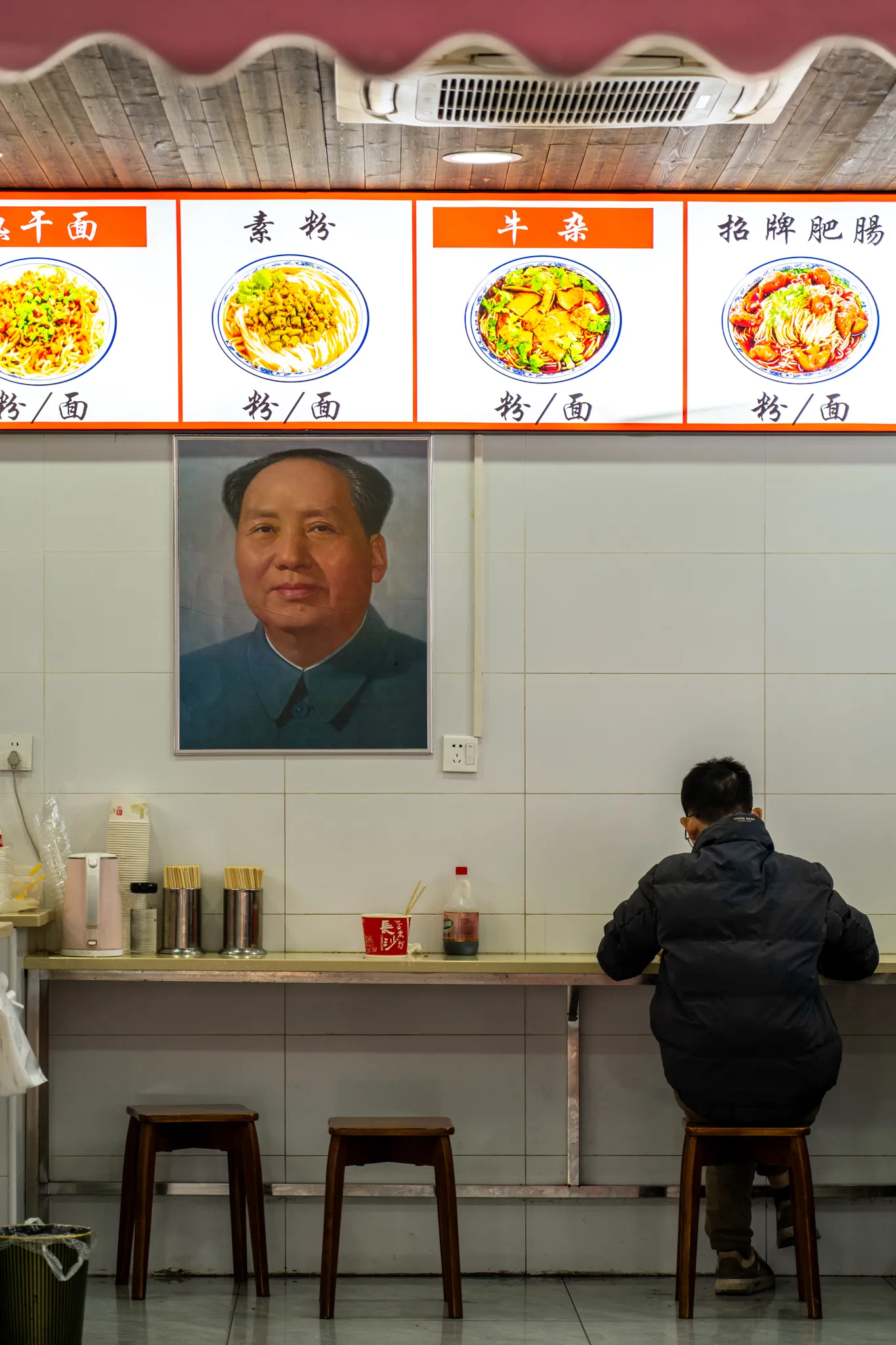 Noodle shop diner beneath a Mao portrait
