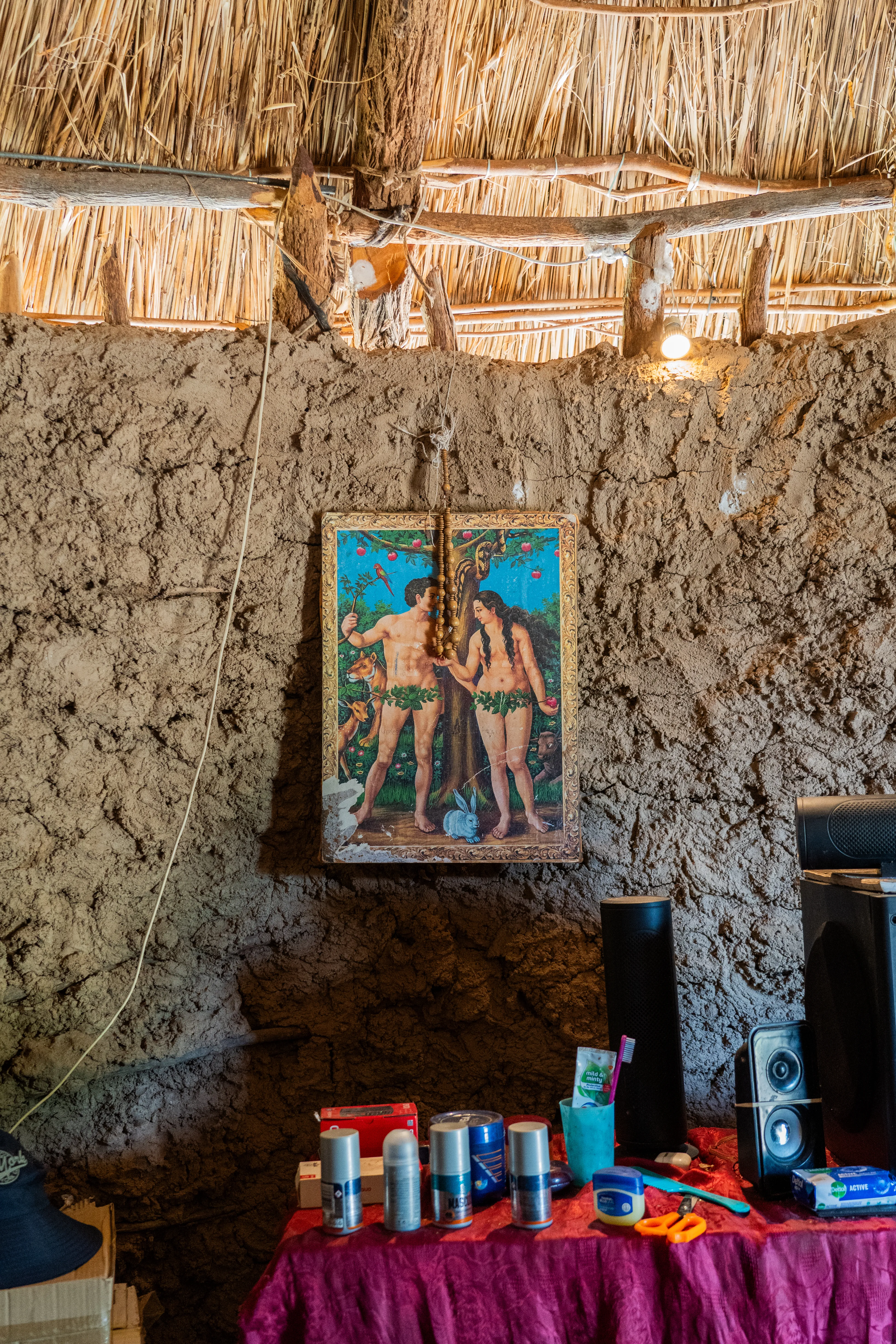 Adam and Eve print hanging inside a mud-walled home, Botswana