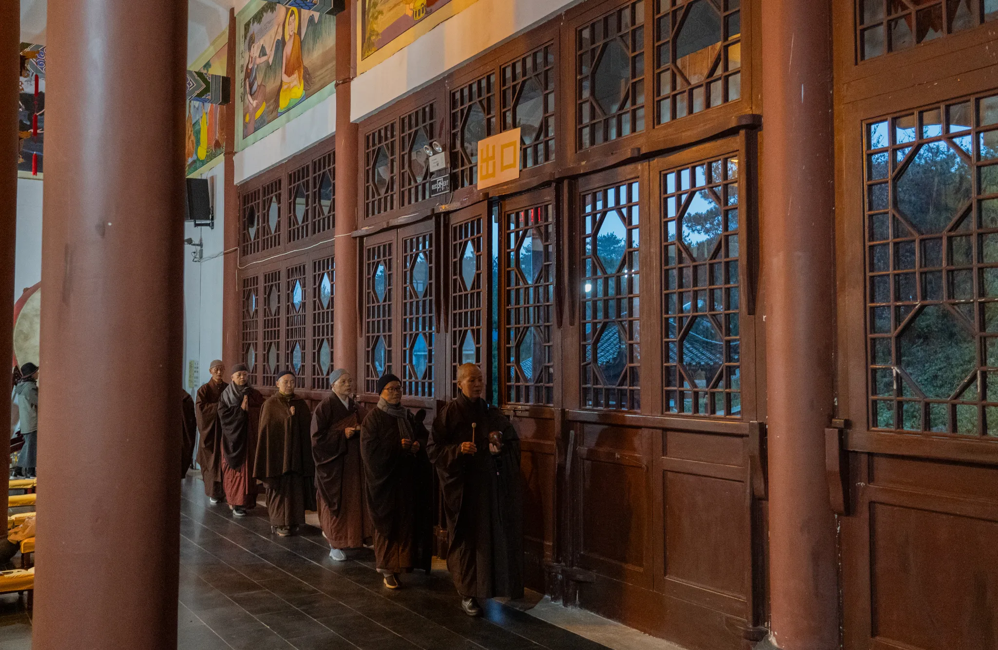Nuns filing past carved temple doors at dusk