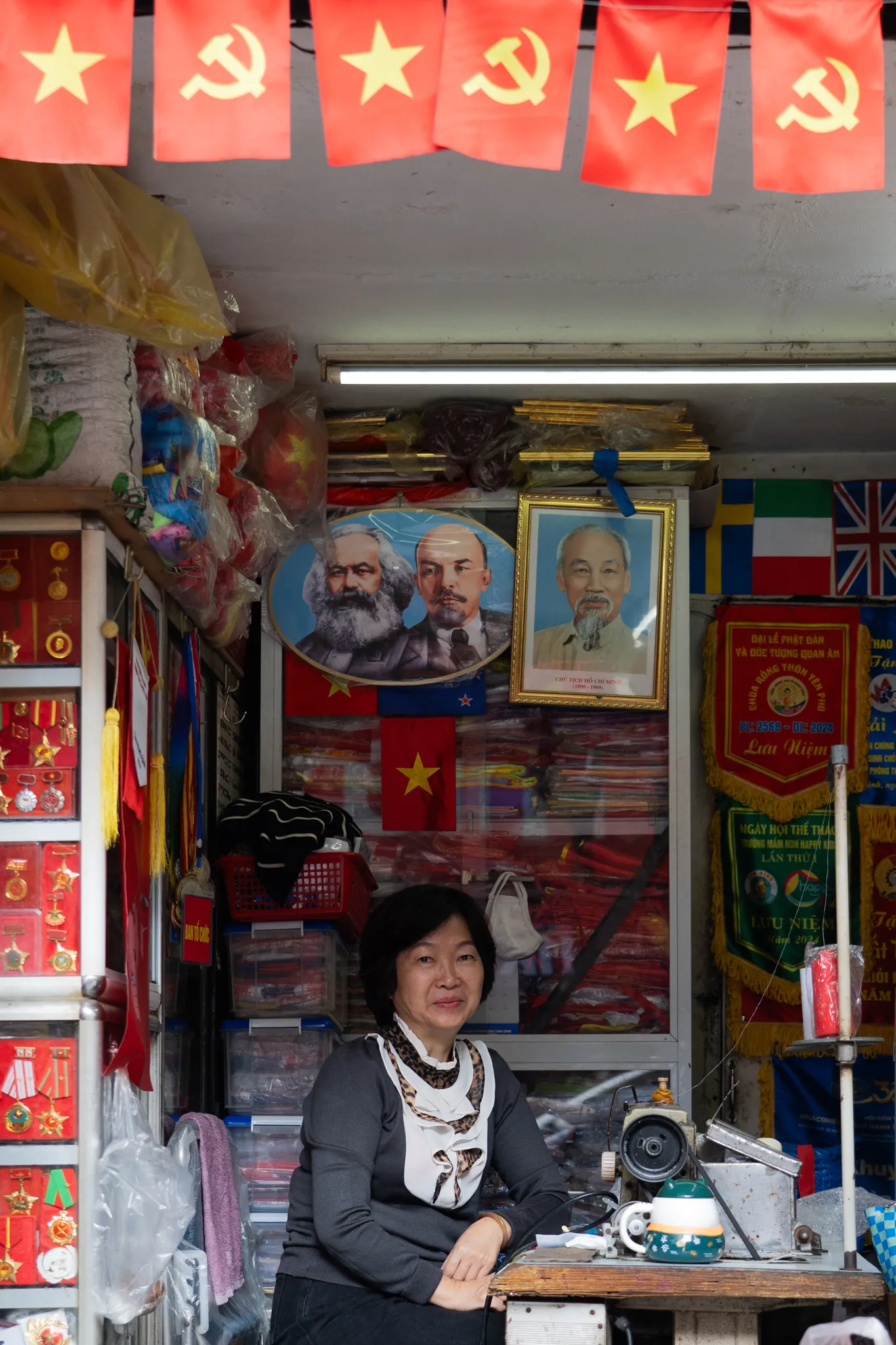 Shopkeeper beneath a portrait of Ho Chi Minh
