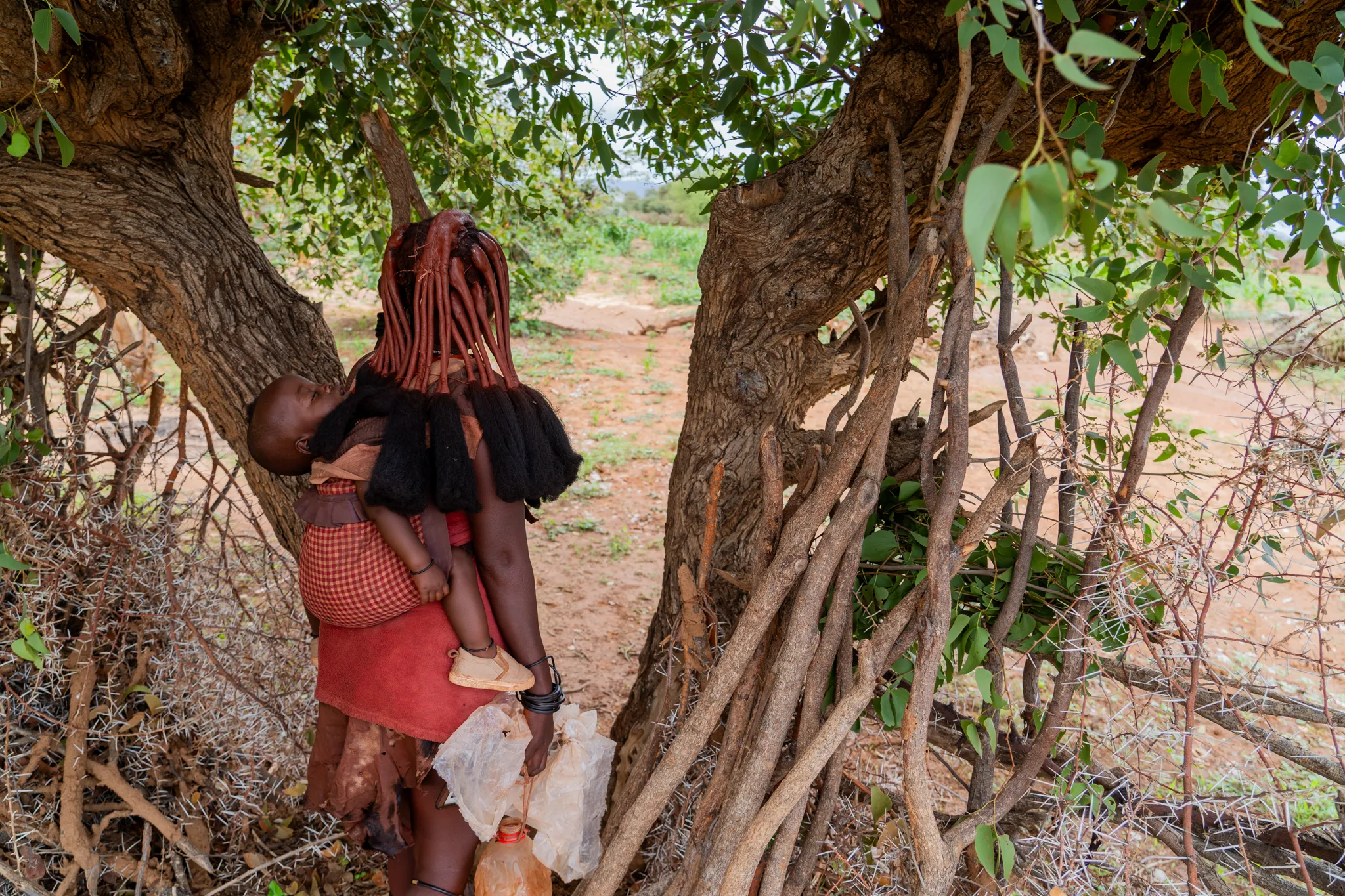 Himba woman carrying her child through her farm, Namibia